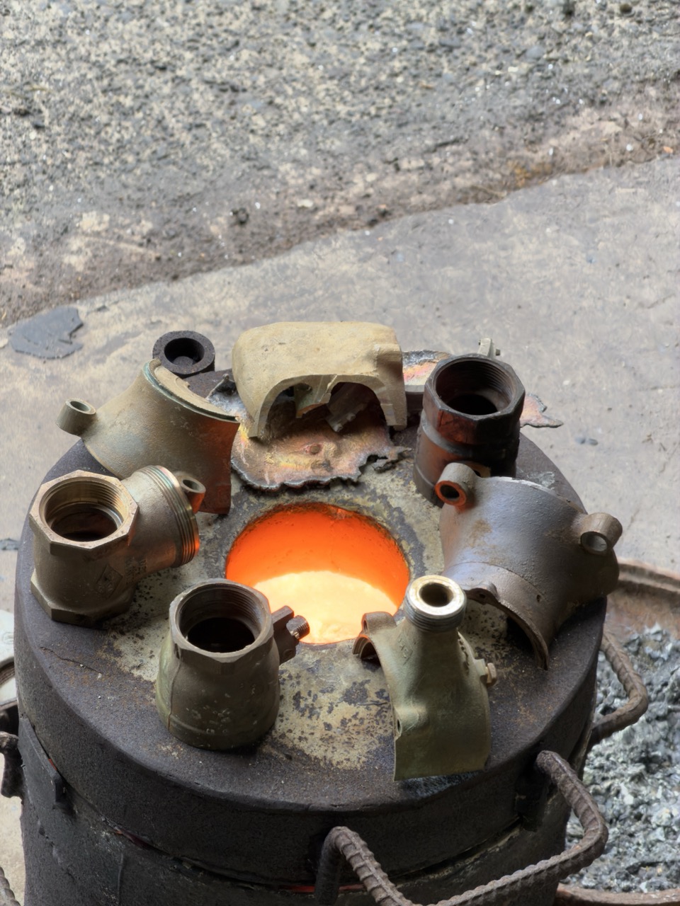 A picture of a furnace with various scrap metal on its edge