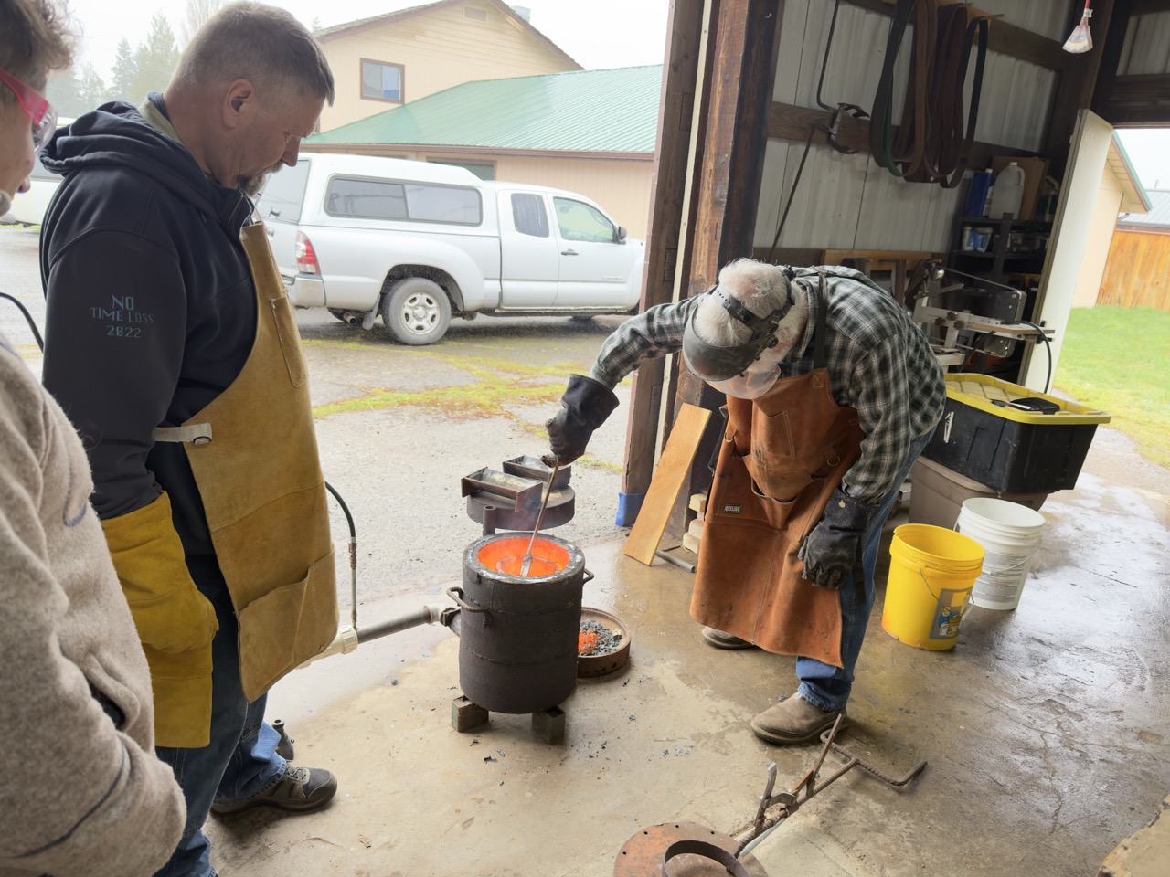 A man dressed in protective gear stirring metal in the furnace